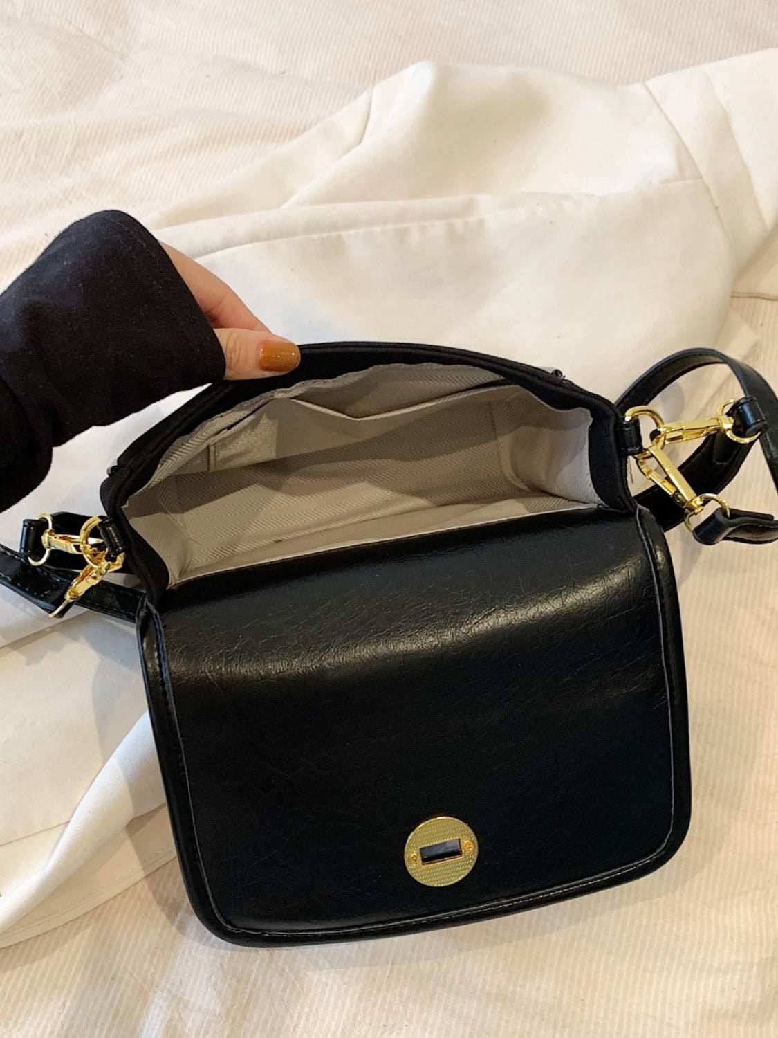 Small black PU leather suede twist-lock shoulder bag, open view showing interior and gold hardware.