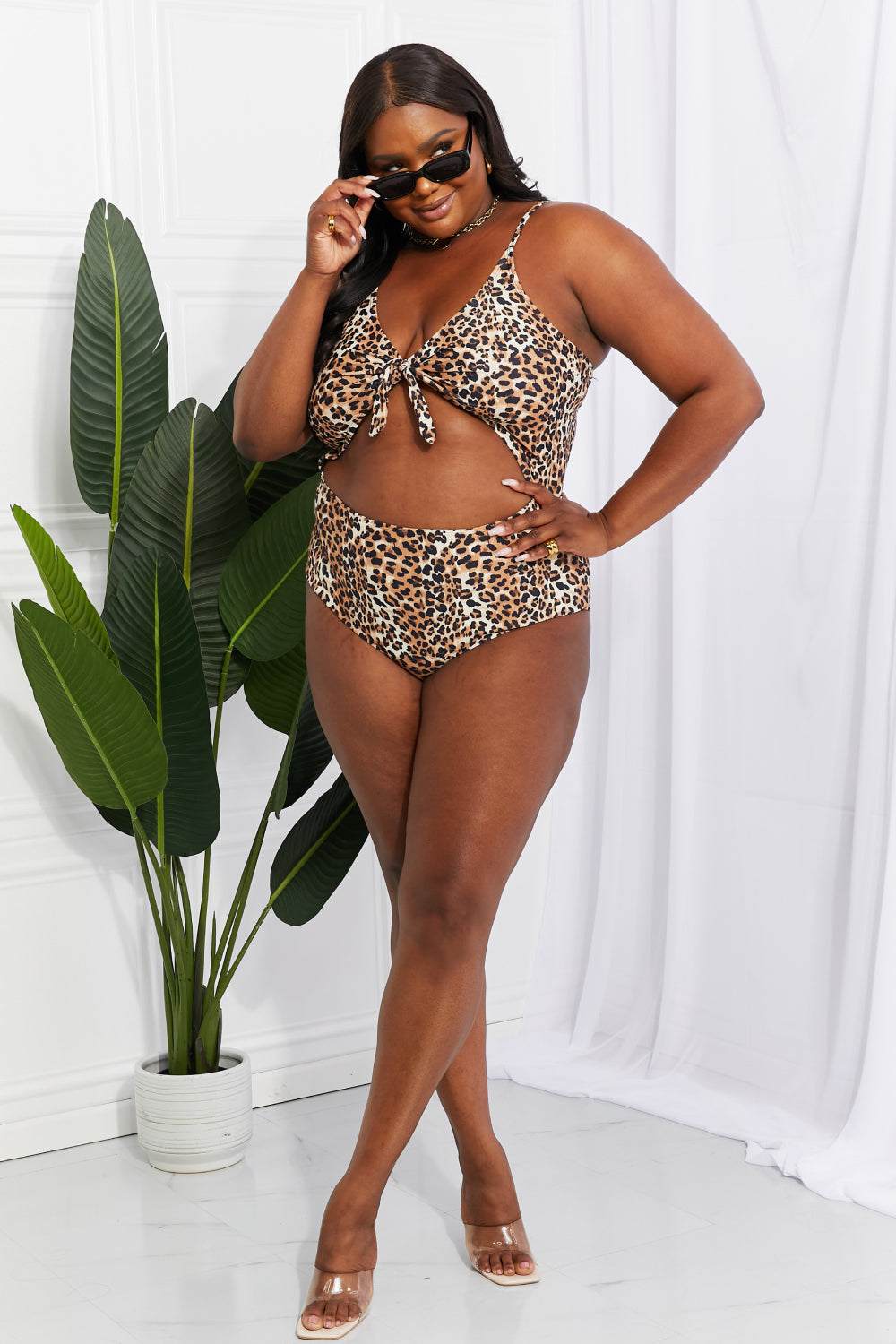 Plus-size model wearing Marina West Swim Lost At Sea leopard print cutout one-piece swimsuit.