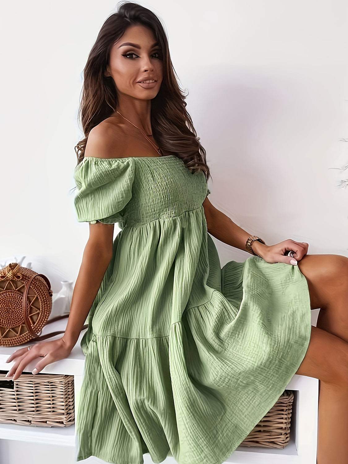 Ruffled off-shoulder short sleeve dress in green, worn by a seated woman.