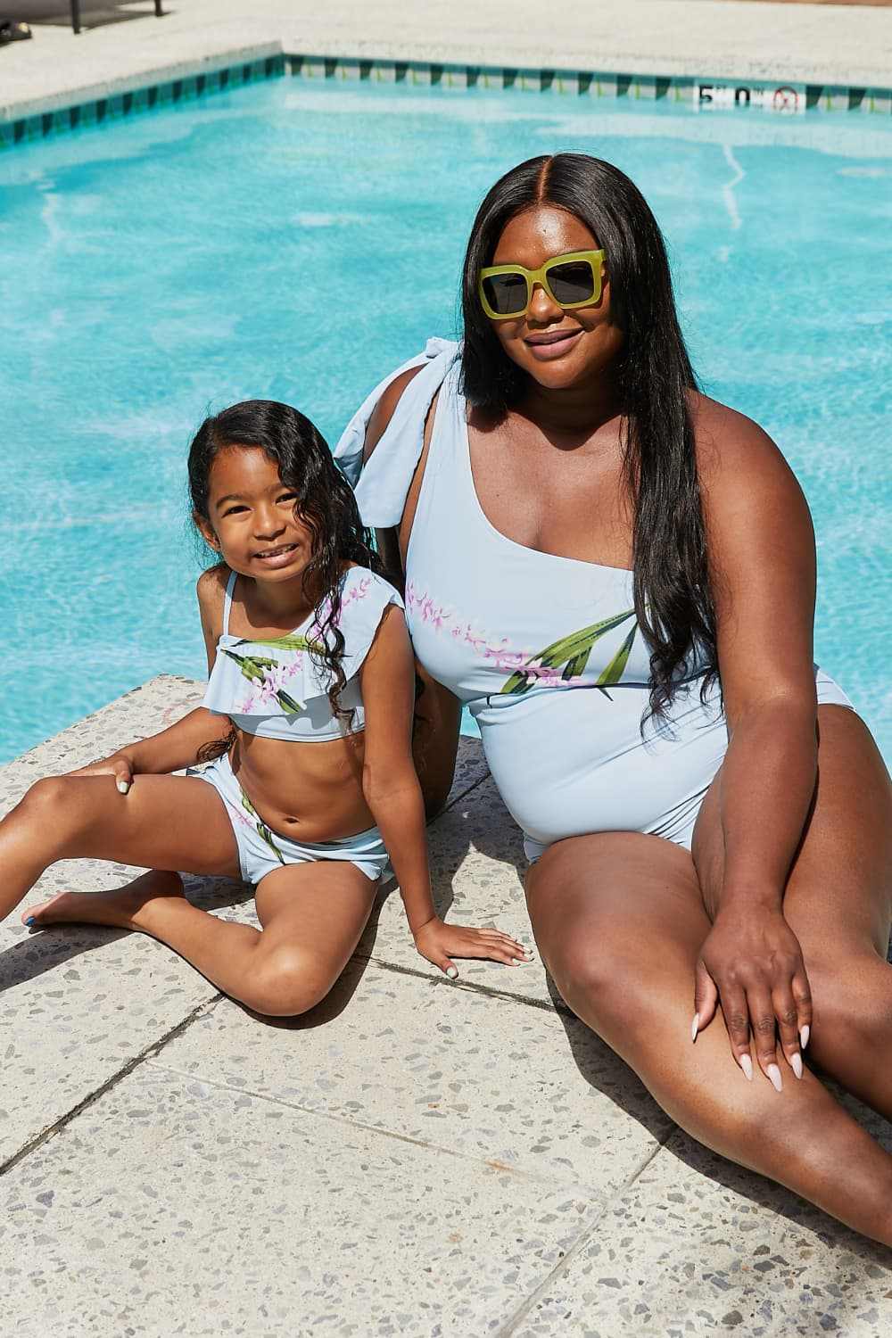 Woman and child by the pool wearing Marina West Swim Vacay Mode one shoulder swimsuits in pastel blue.