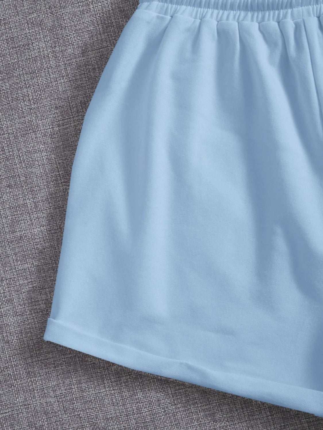 Light blue drawstring pocketed elastic waist shorts on a gray background.