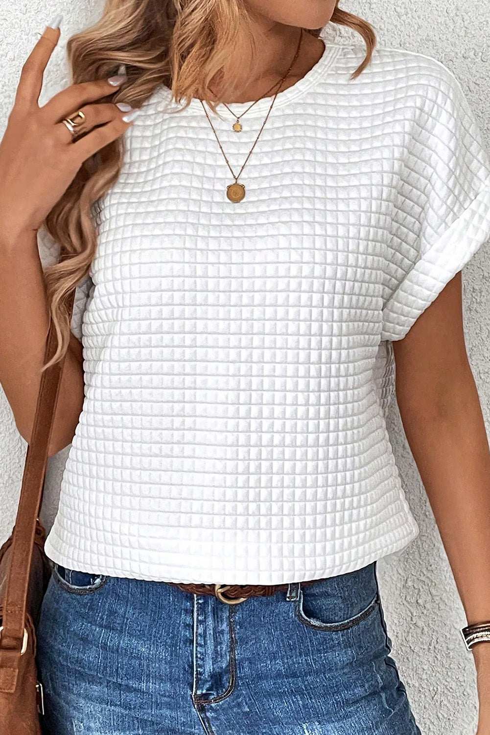 Round neck short sleeve white t-shirt with textured fabric, paired with blue jeans.