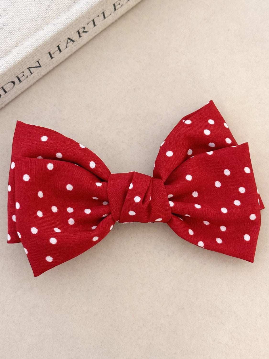 Red polka dot bow hair clip with polyester fabric, 4.7 in long.