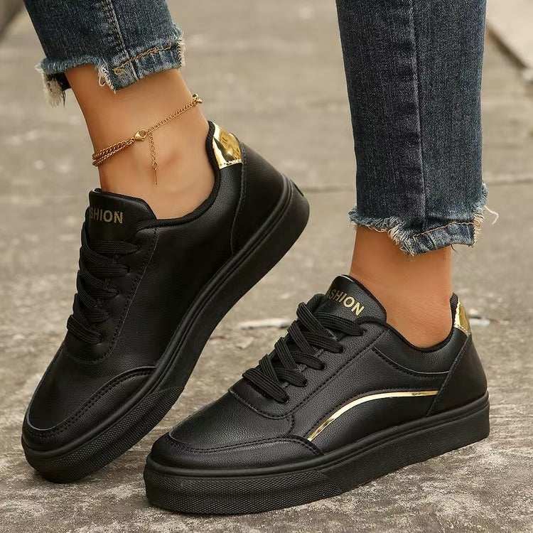 PU leather round toe flat sneakers in black, shown worn with jeans.