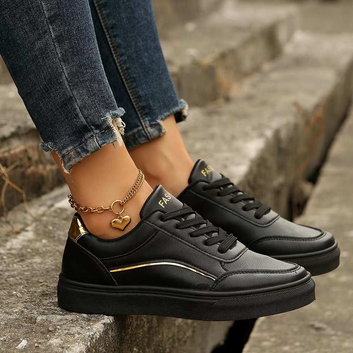 PU leather round toe flat sneakers worn with jeans, featuring black and gold detailing.