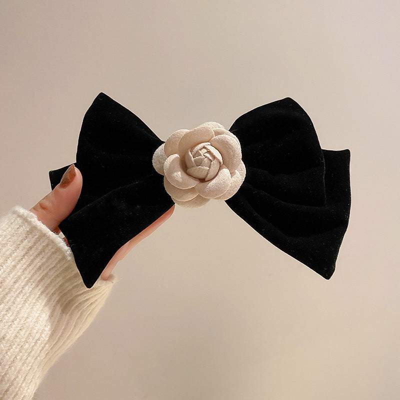 Black bow hair clip with rose trim detail, made from alloy and polyester, measuring 6.8 x 4.2 inches.