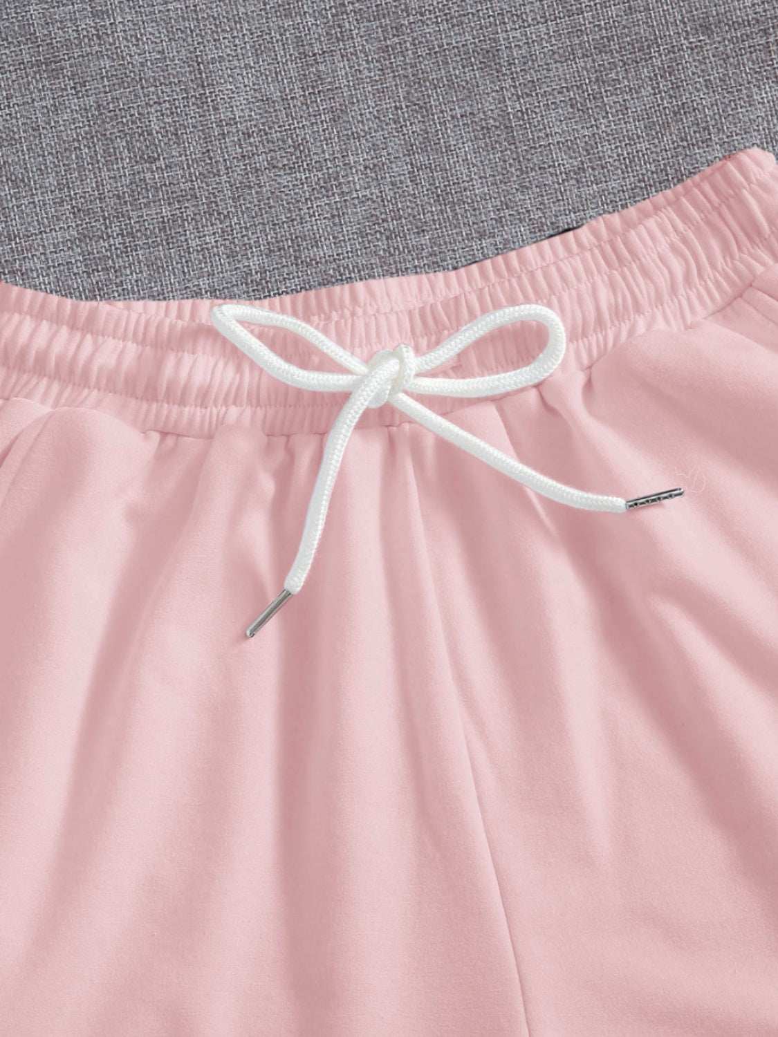 Drawstring pocketed elastic waist shorts in pink with white drawstring.