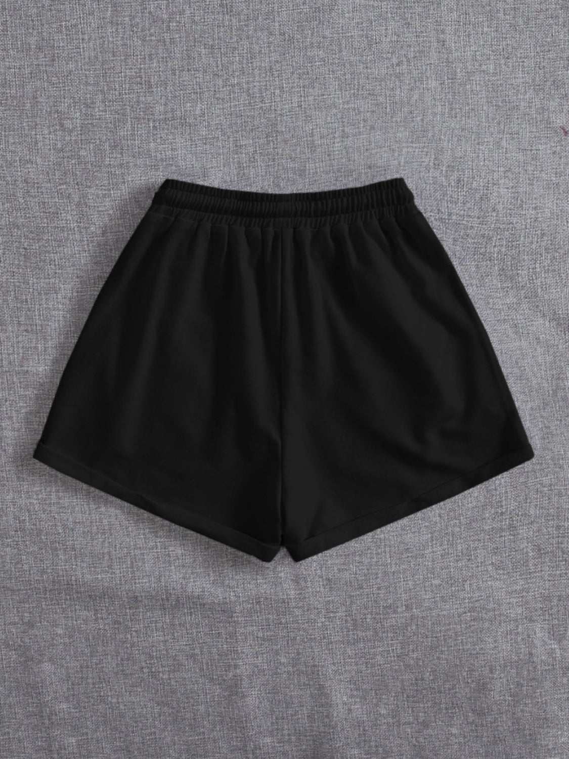 Black drawstring pocketed elastic waist shorts made of 100% polyester on grey background.